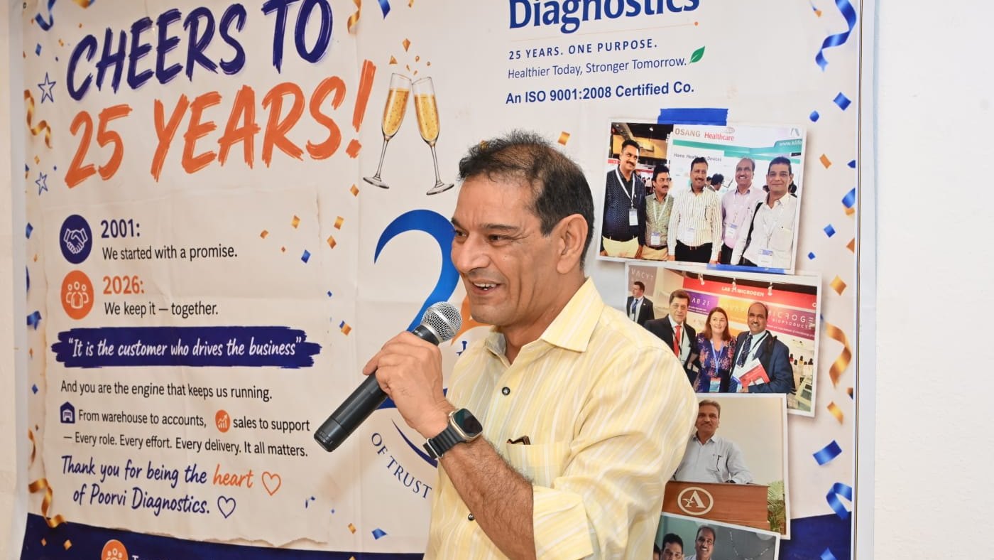Deepak, GM Sales of Poorvi Diagnostics, speaking at the Silver Jubilee celebration in front of the Cheers to 25 Years banner